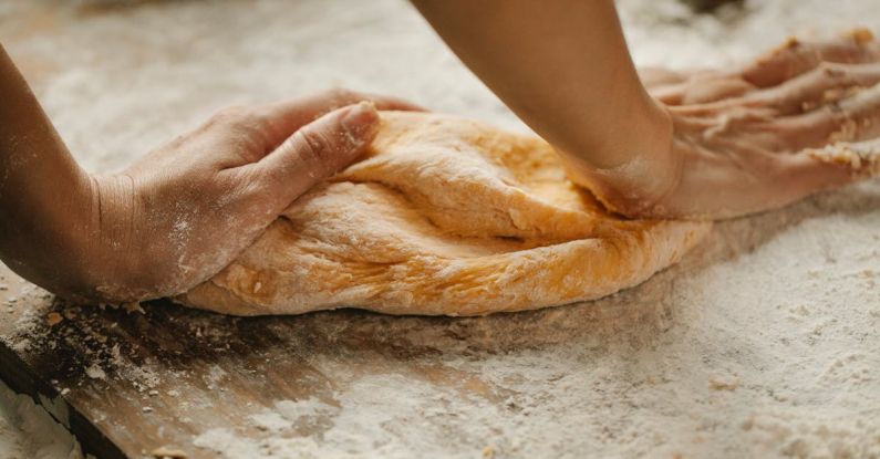 Home Chef - Unrecognizable female kneading soft fresh egg dough on cutting board with flour in kitchen