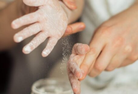 Family Recipes - Happy crop cute girl with pigtail and blurred father shaking off flour from hands while making dough