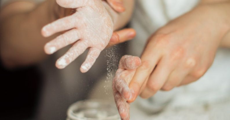 Family Recipes - Happy crop cute girl with pigtail and blurred father shaking off flour from hands while making dough