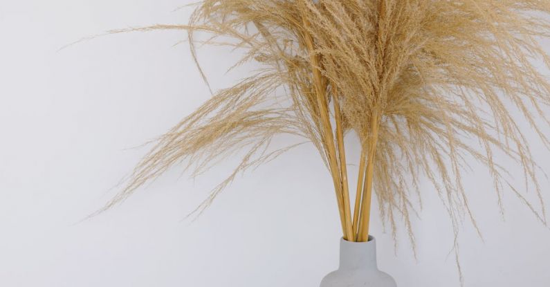 Religious Events - Golden plant with lush leaves and thin stems put in vase near wooden table mat with egg box and painted eggs inside for Easter celebration