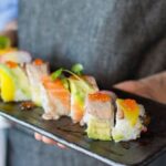 Traditional Chefs - Person Holding Sushi on Black Plate