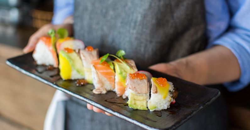 Traditional Chefs - Person Holding Sushi on Black Plate