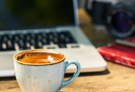 Coffee Culture - A cup of coffee and a camera on a wooden table in the workplace