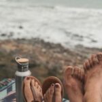 Coffee Waves - Couple Sitting on Picnic Blanket Near Body of Water