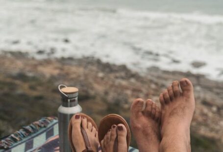 Coffee Waves - Couple Sitting on Picnic Blanket Near Body of Water